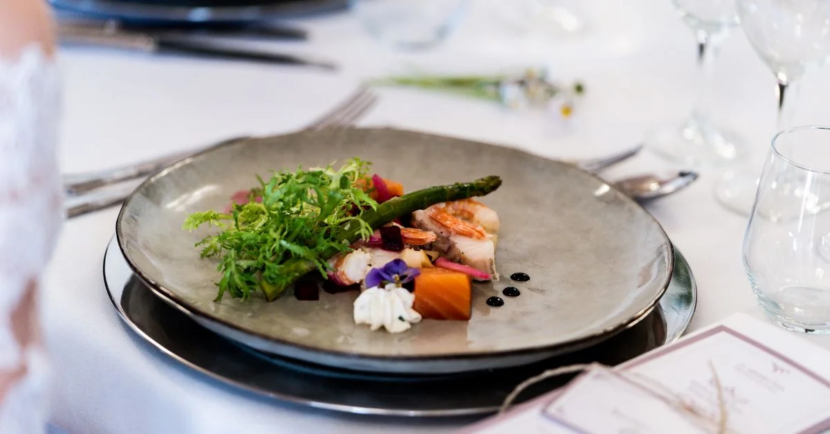 Un plat gourmet avec des légumes et une sauce élégamment présenté dans un cadre de table sophistiqué.