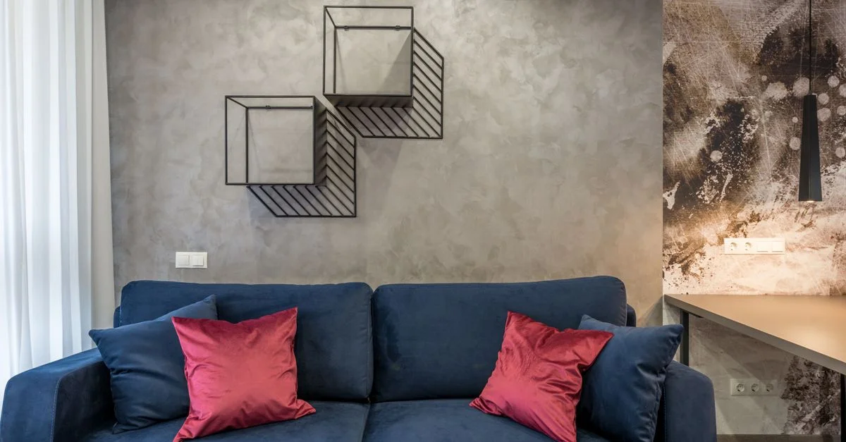 Salon confortable avec un canapé bleu, des coussins rouges et des œuvres d'art abstrait créant une esthétique moderne.