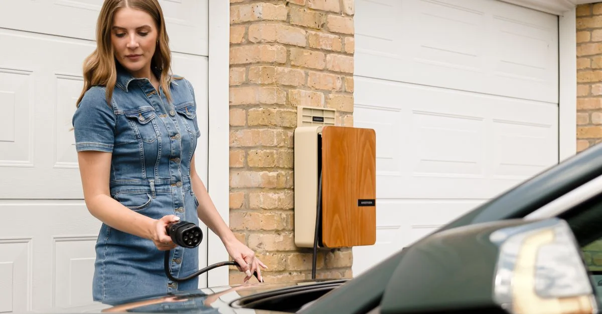Une femme branche un chargeur de véhicule électrique à une station de recharge domestique.
