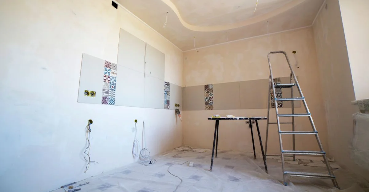 Vue intérieure d'une pièce en rénovation avec peinture, carrelage et outils.