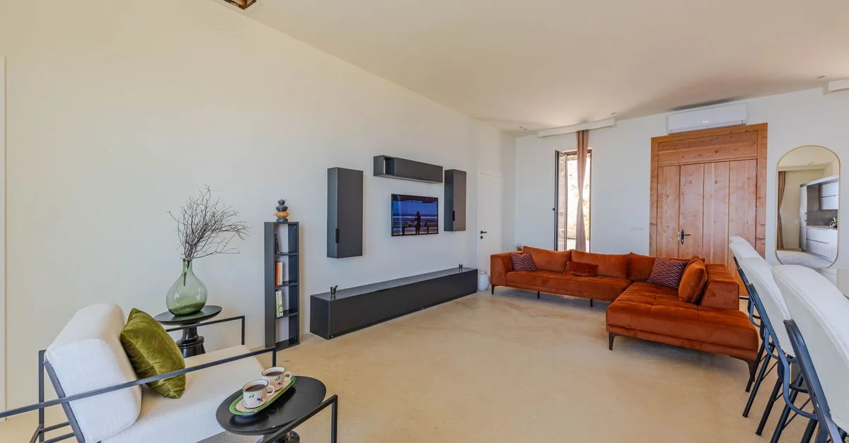 Salon minimaliste lumineux et aéré avec un élégant canapé orange et une décoration contemporaine.