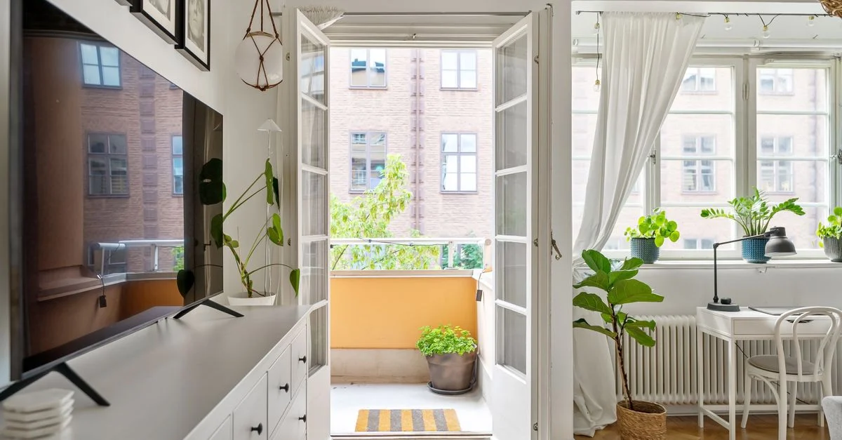 Salon de style scandinave confortable avec un balcon ensoleillé et une décoration moderne.