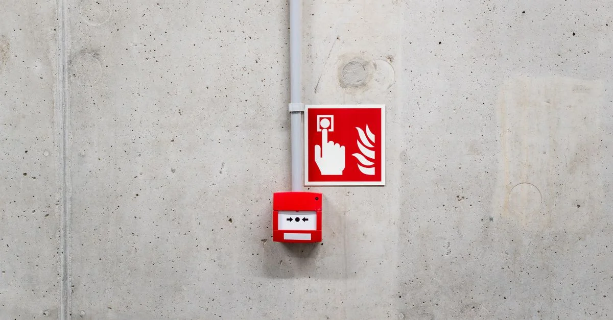 Alarme incendie rouge d'urgence sur un mur en béton gris à Poznań, renforçant la sensibilisation à la sécurité.