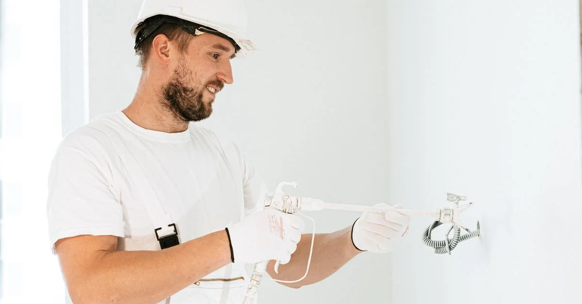 Électricien portant des équipements de sécurité en installant des câbles dans un nouveau bâtiment.