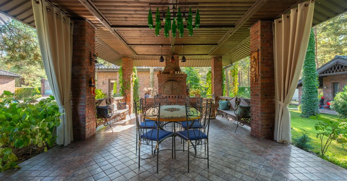 Charmant patio avec mobilier en fer forgé, murs en briques et vue sur le jardin, idéal pour se détendre en plein air.