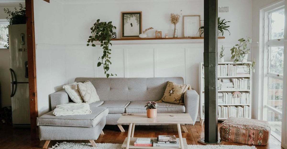 Salon lumineux et confortable avec un design scandinave et une décoration moderne, comprenant un canapé et des plantes.