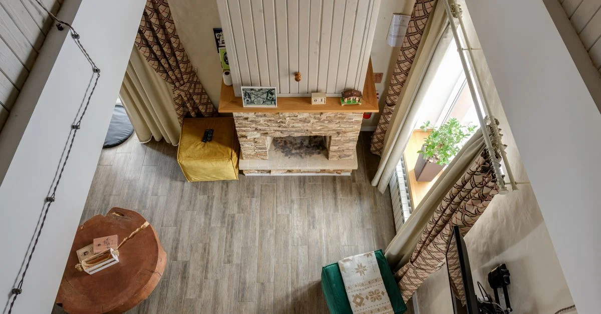 Vue en hauteur d'un salon élégant avec une cheminée rustique et un sol en bois, mettant en avant un design d'intérieur moderne.