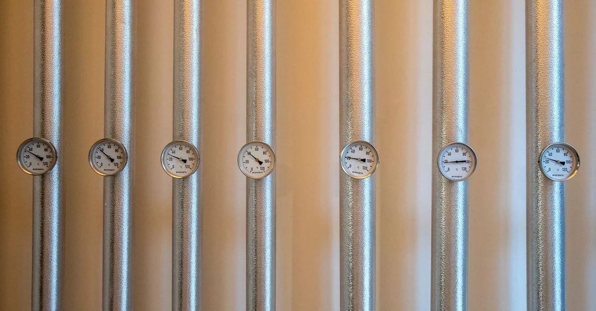 Gros plan sur des conduits métalliques argentés industriels avec des cadrans blancs.