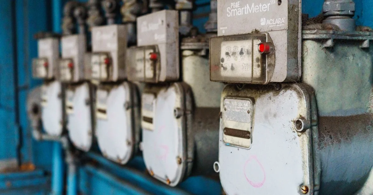 Plusieurs compteurs intelligents alignés sur un mur industriel bleu.