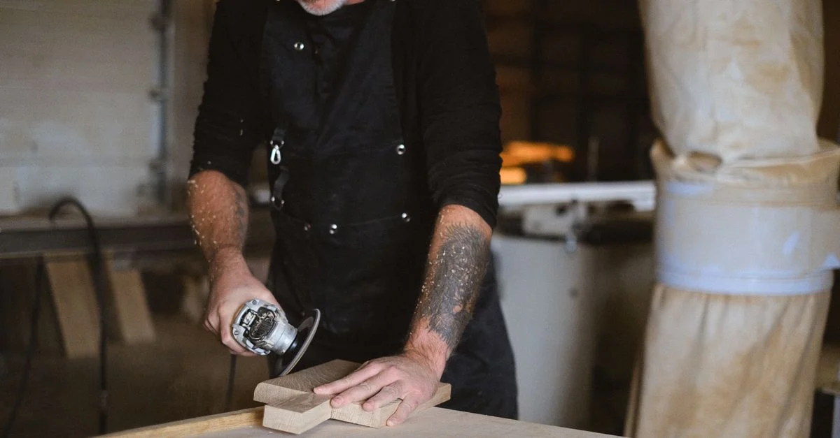 Un artisan qualifié ponce une planche de bois dans un atelier de menuiserie bien équipé.