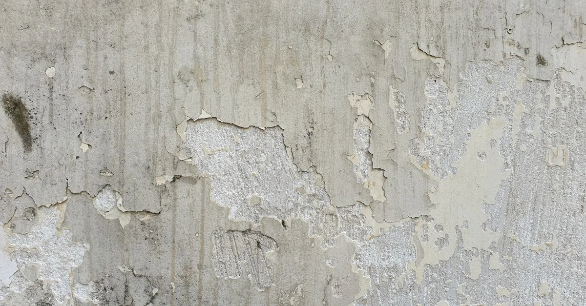 Gros plan d'un mur en béton usé avec de la peinture écaillée, mettant en valeur la texture grunge.