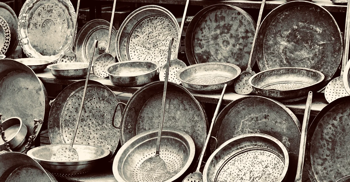 Une collection d'ustensiles de cuisine en métal vintage, y compris des casseroles et des louches avec des motifs complexes.