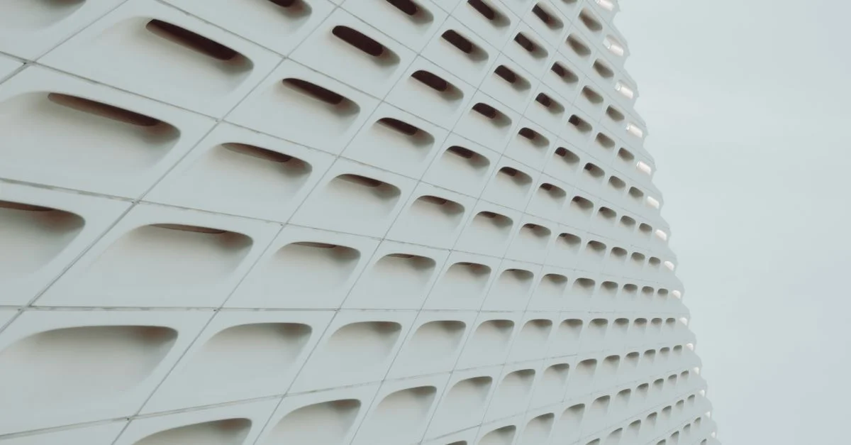 Vue abstraite d'une façade de bâtiment géométrique blanche avec un design à motif de grille.